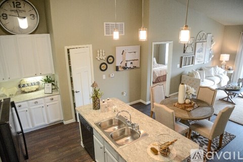 A kitchen with a clock on the wall and a dining area with chairs and a table.