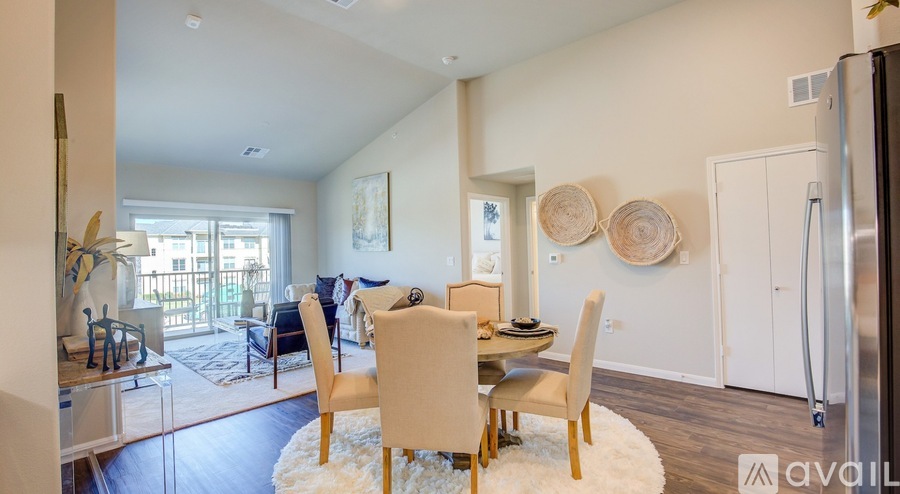 A dining room with a white rug and wooden chairs.