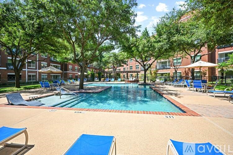 A pool surrounded by trees and chairs with a building in the background.