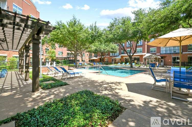 A pool area with a shaded seating area and a building in the background.