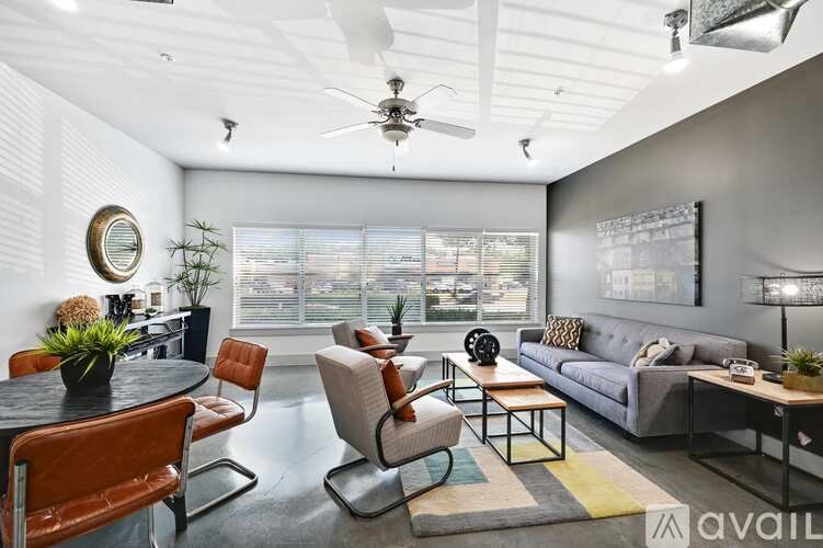 A living room with a grey couch, a black table, and a ceiling fan.