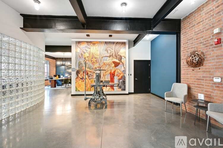 A room with a large painting, a chair, and a table.
