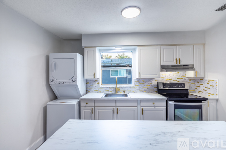 A kitchen with a marble countertop and white cabinets.