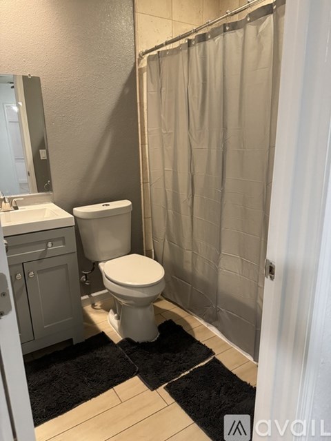 A bathroom with a toilet, sink, and shower curtain.