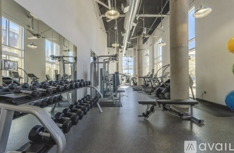 A gym with a variety of equipment including dumbbells, weight machines, and benches.