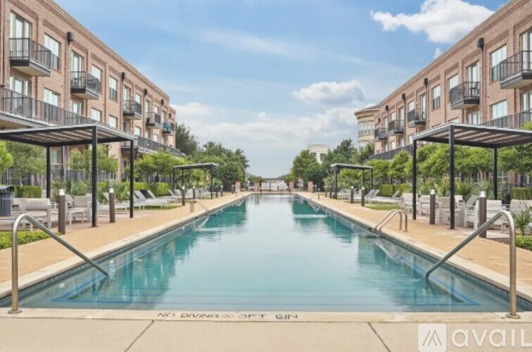 A long rectangular pool surrounded by apartment buildings and lounge chairs.