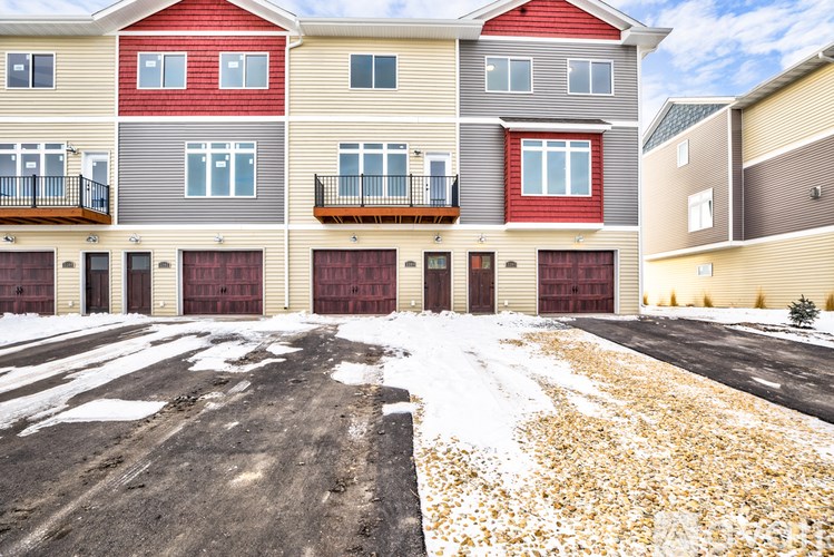 A large multi-story building with a red roof and a parking lot in front.