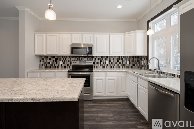 A kitchen with white cabinets and a marble countertop.