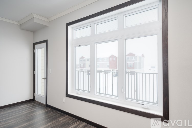 A room with a large window overlooking a balcony with a view of buildings.