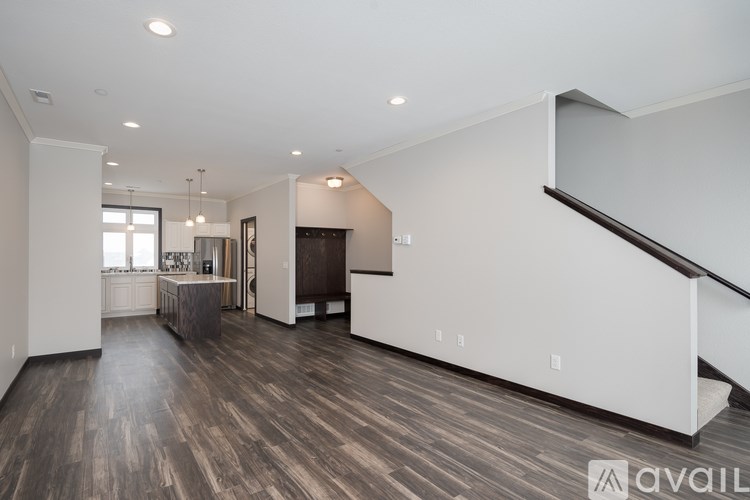 A spacious living room with wood flooring and a staircase on the right side.