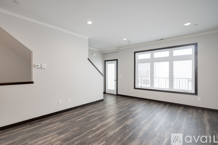 A spacious room with wooden flooring and a large window.