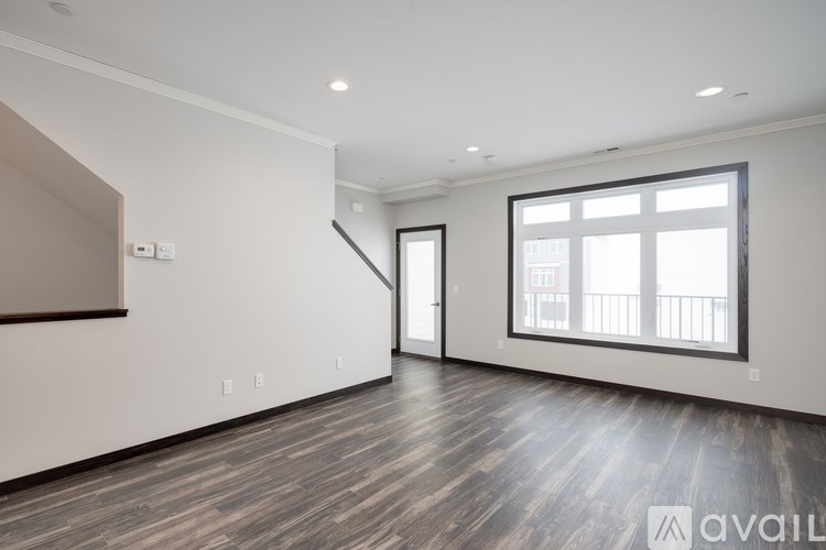 A spacious room with wooden flooring and a large window.