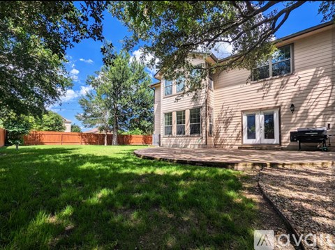 A house with a green lawn and trees in the background.