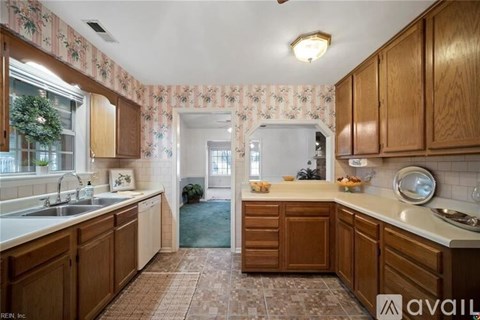 A kitchen with wooden cabinets and a floral wallpaper.