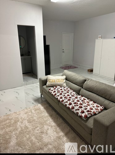 A living room with a grey couch and a pillow that says "Stay Cool".