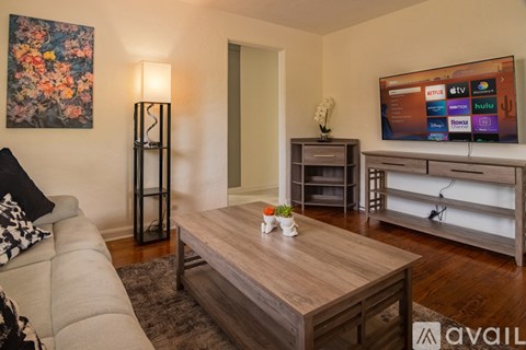 A living room with a couch, a coffee table, and a television displaying streaming services.