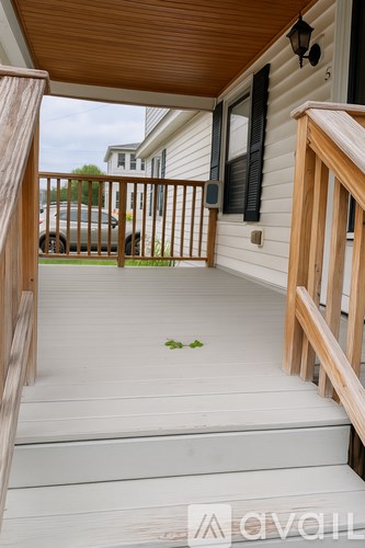 A wooden deck with a white railing and a leaf on the floor.