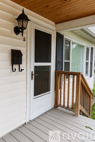 A white door with a black handle and sidelights on a wooden porch.