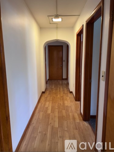 A long hallway with wooden floors and a door at the end.