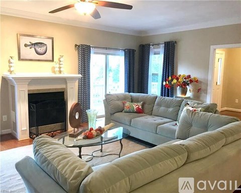 A living room with a grey couch and a fireplace.