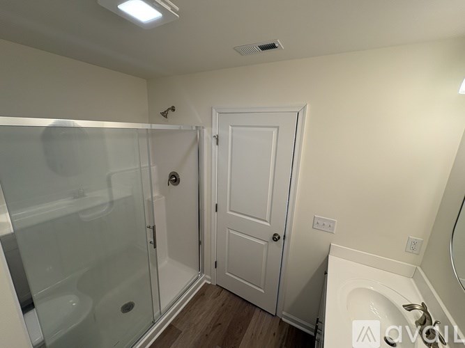 A white bathroom with a glass shower door and a white sink.