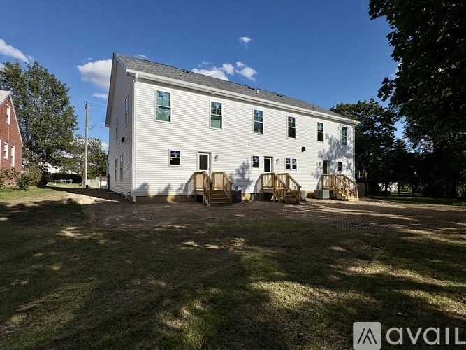 A white barn with a cobblestone driveway in front of it.