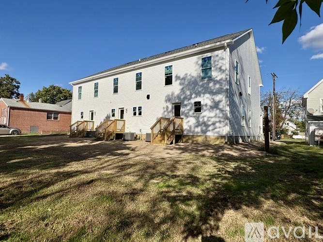 A white building with a brown roof and a sign that says "avail" on the grass in front of it.