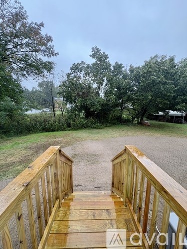 A wooden deck overlooks a grassy area with trees.
