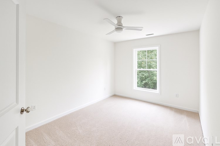A room with a window and a fan on the ceiling.