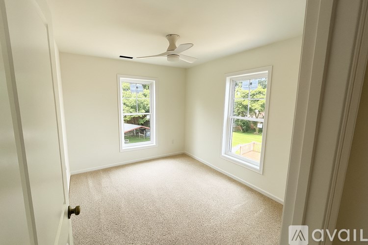 A room with a carpet floor and two windows.