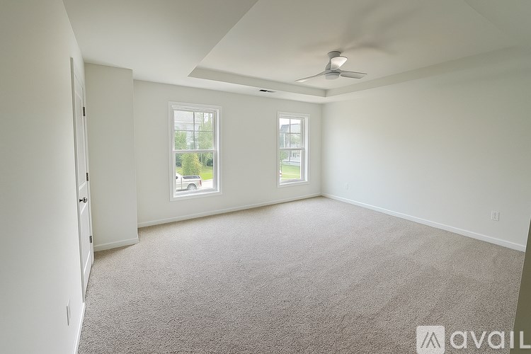 A room with a carpeted floor and a ceiling fan.