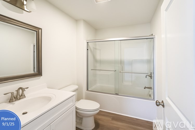 A white bathroom with a toilet, sink, and shower.