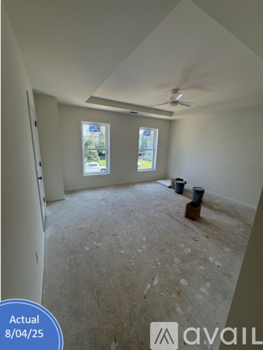 A room with a fan and two windows is under construction.