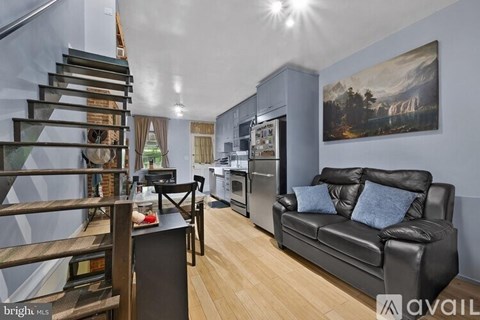 A living room with a black couch and a painting on the wall.