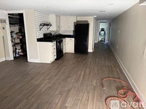 A kitchen with white cabinets and a black fridge is shown.