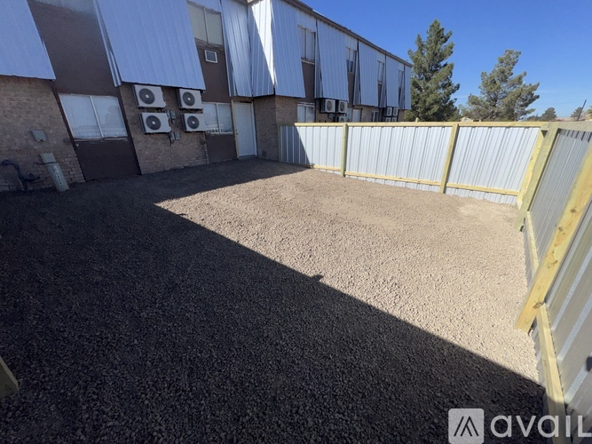 A gravel yard in front of a building with a fence.