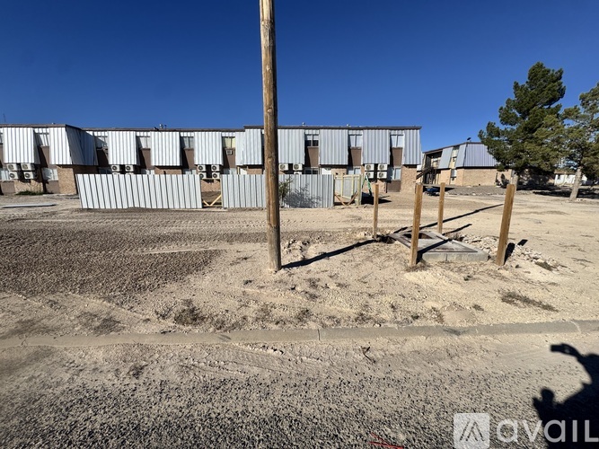 A playground with a wooden swing set in the foreground and a building in the background.