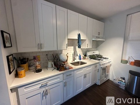 A kitchen with white cabinets and a lot of items on the counter.