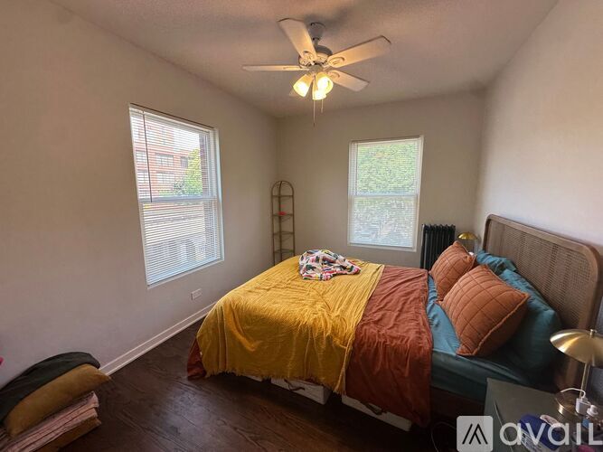 A bedroom with a bed covered in a yellow and orange comforter.