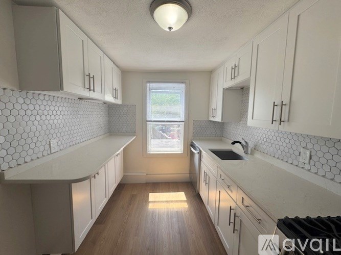 A kitchen with white cabinets and a window.