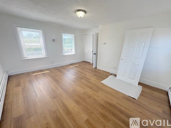 A room with wooden flooring and white walls.