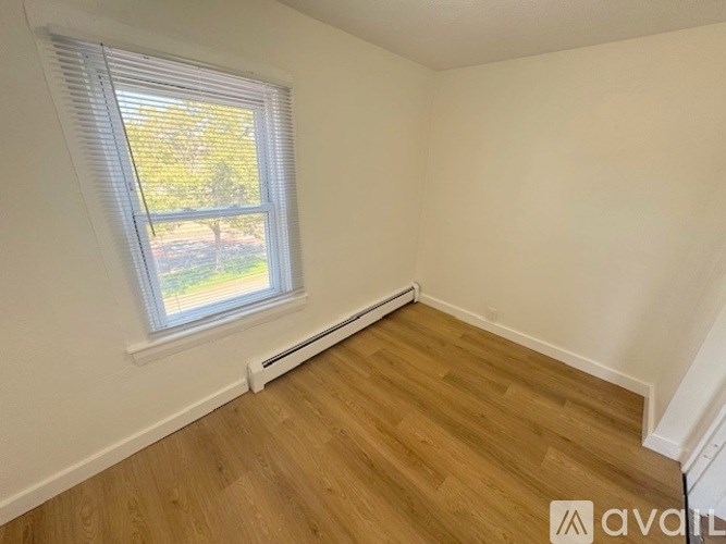 A room with wooden flooring and a window with blinds.