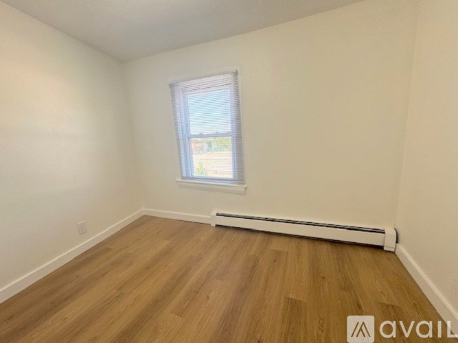 A room with wooden flooring and a window with blinds.