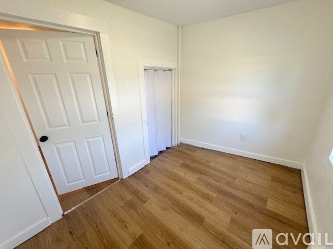 A room with a white door and wooden flooring.
