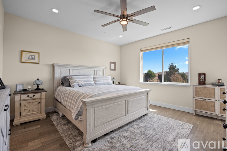 A bedroom with a large bed, a dresser, and a ceiling fan.