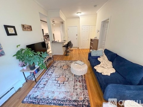 A living room with a blue couch and a rug.