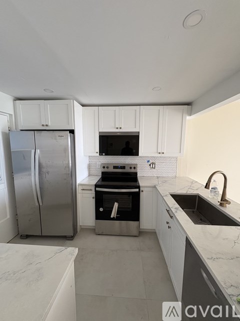 A kitchen with a refrigerator, oven, and sink.