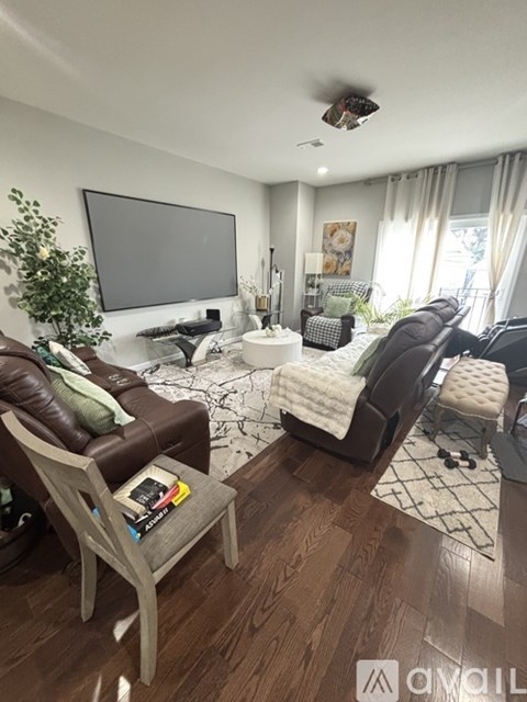 A living room with a brown leather couch and a white chair.
