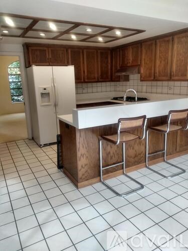 A kitchen with white tiled floors and wooden cabinets.