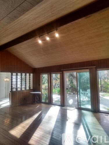 A room with wooden floors and ceiling, and a table with chairs.